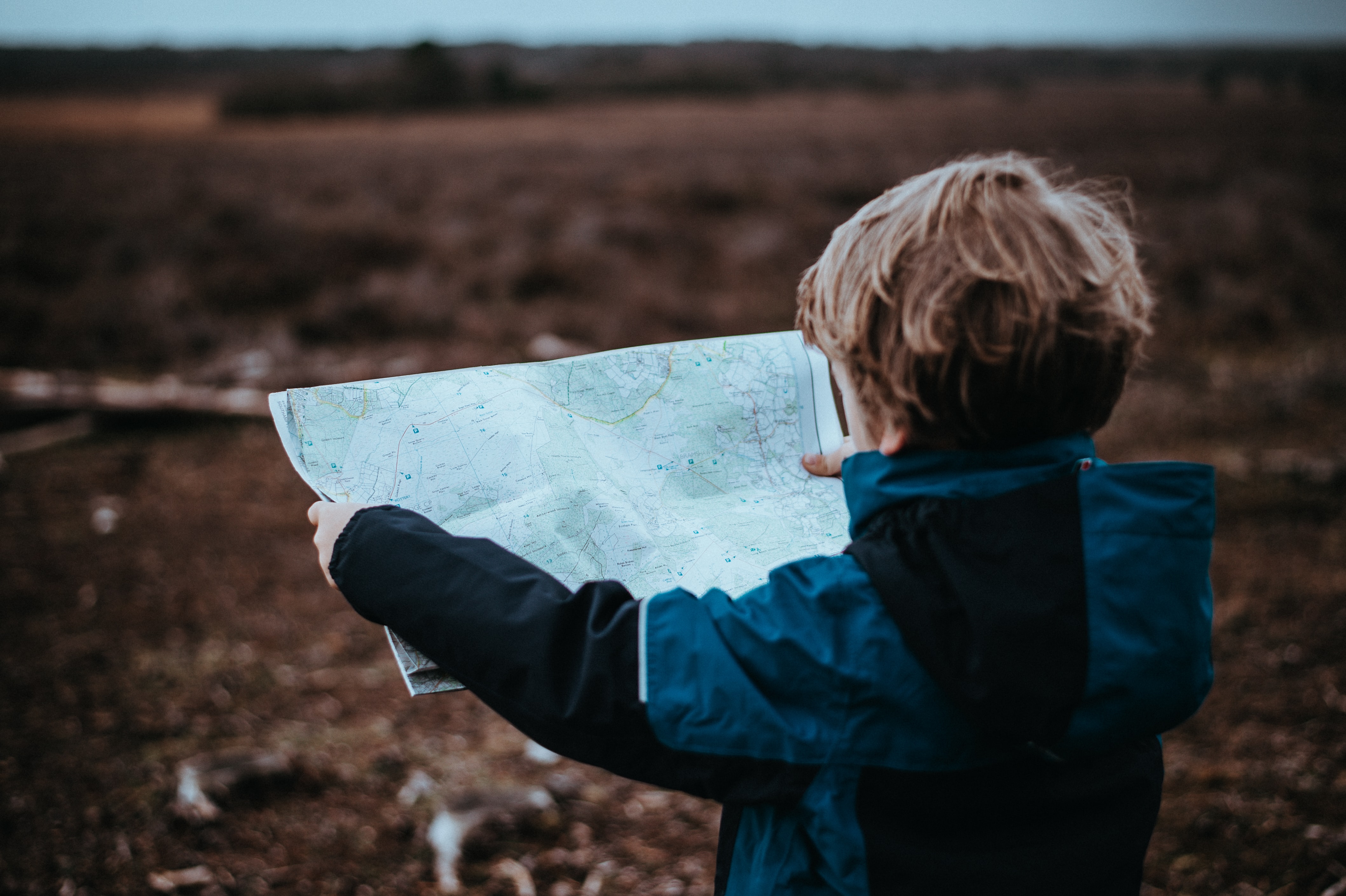 Kid holding a map looking out at the land